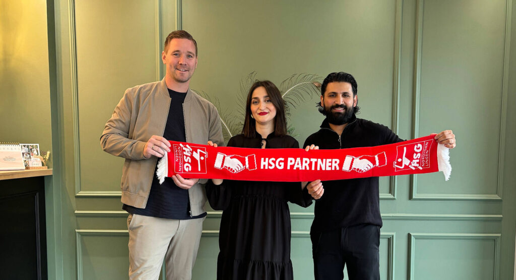 Das Bild zeigt die beiden Inhaber des Friseur Salons "by.KARA" und einen Vertreter der HSG Nordhorn-Lingen. Sie halten alle drei zusammen einen Fanschal der HSG Nordhorn-Lingen, in der Mitte steht dann noch "HSG Partner" drauf.