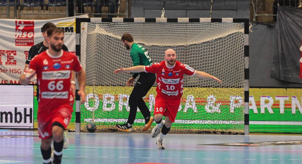 Das Bild zeigt einen Spieler der HSG Nordhorn-Lingen. Der Spieler hat die Arme weit ausgestreckt und jubelt über das geworfene Tor.